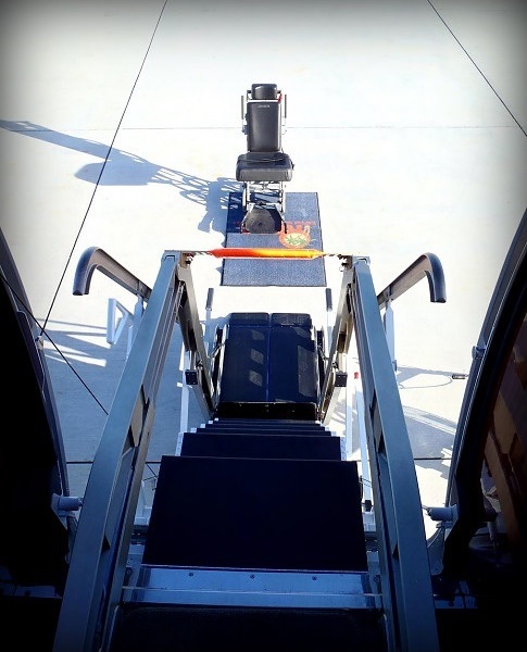 Passenger in an aisle wheelchair boarding a private jet using a hydraulic lift